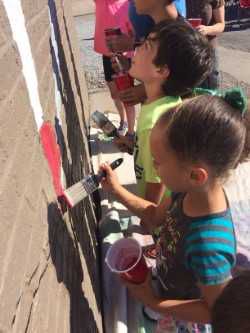 Kids help painting mural on Whiteland building